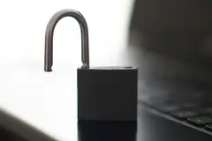 Отворен метален катинар до клавиатурата на лаптоп на тъмна повърхност, на светъл размит фон